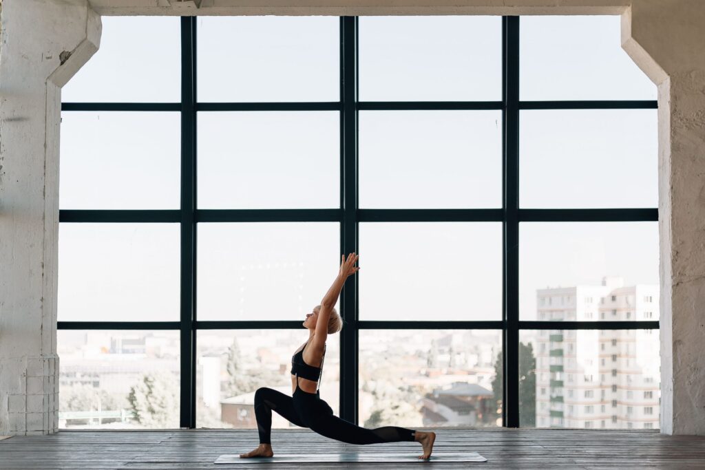 women practising yoga in the construction building by the big windows