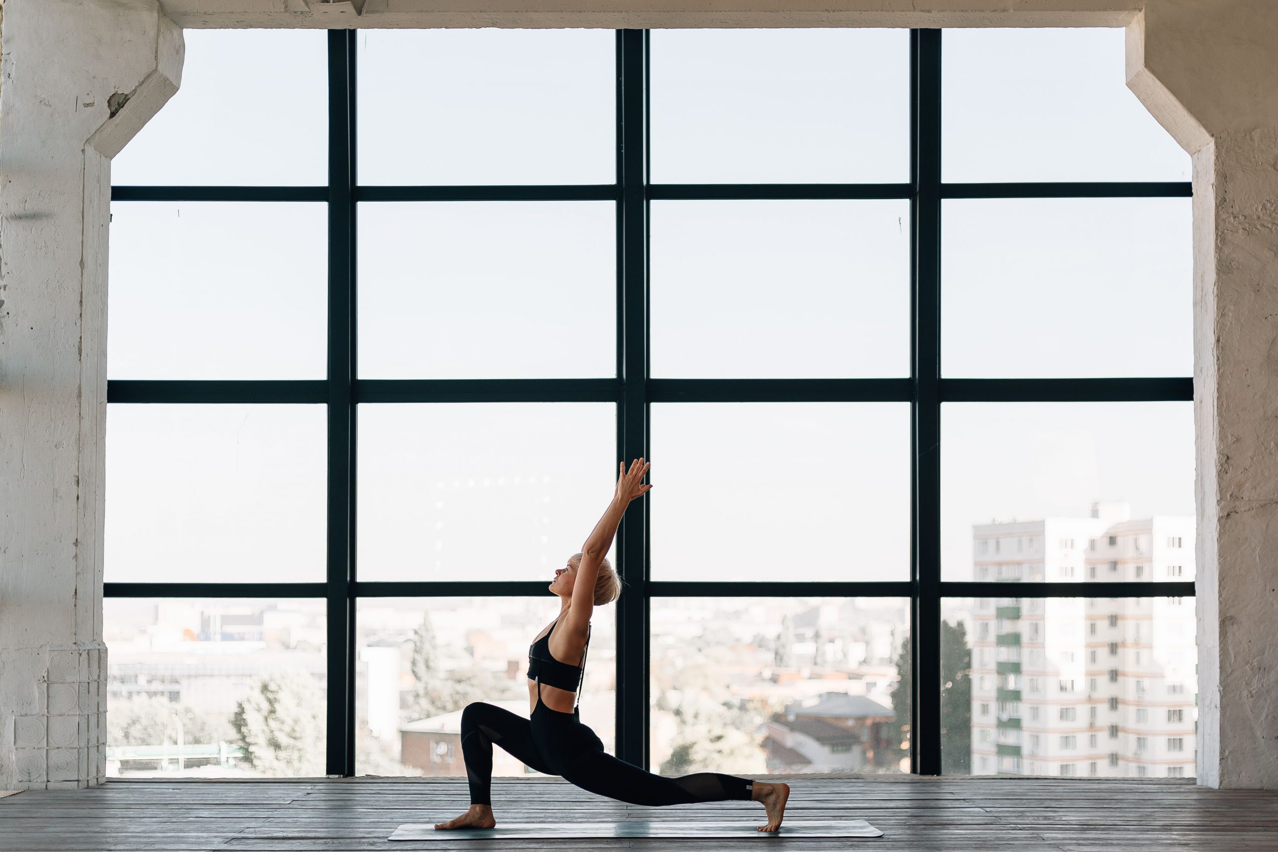 Een vrouw in een yoga pose voor een raam