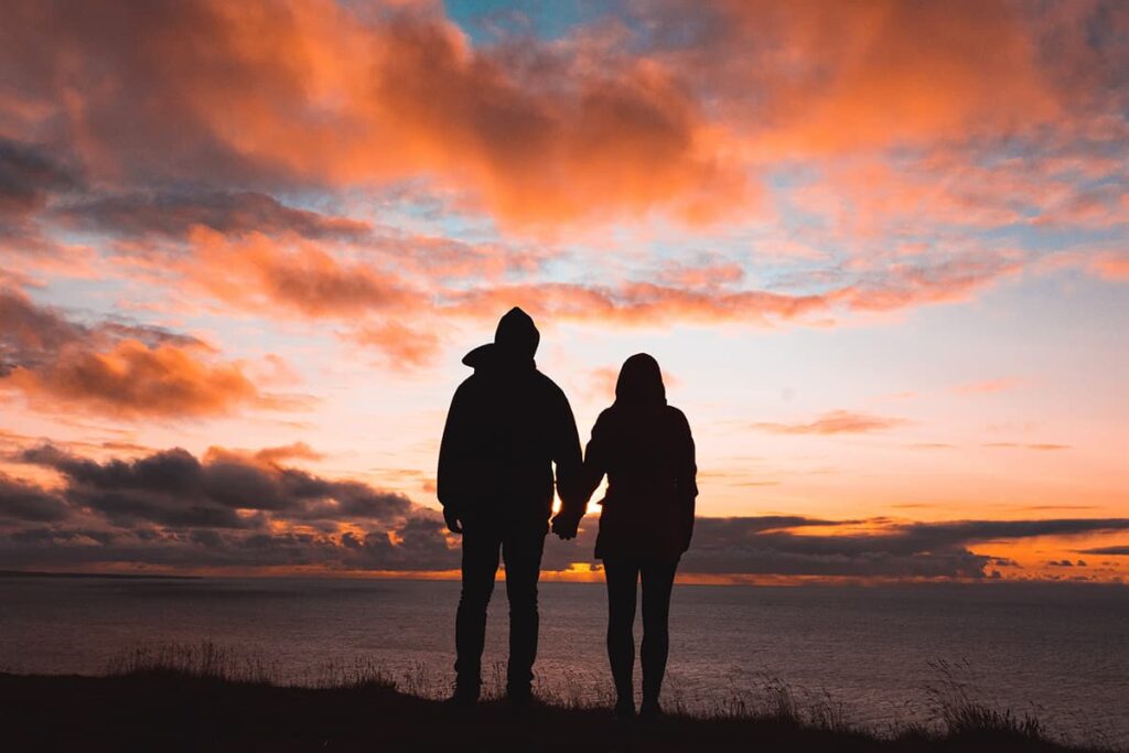 couple holding hands while watching a sunset