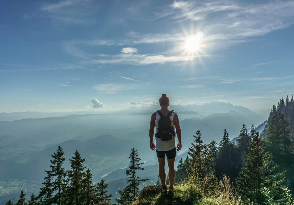 A man standing on the top of the mountain overviewing the Forrest