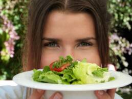 Een lachende vrouw die poseert met een salade