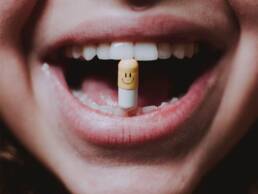Een vrouw die een capsule in haar mond houdt met een gelukkig gezicht erop getrokken