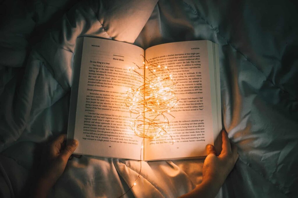 person holding a book with fairy lights on the book