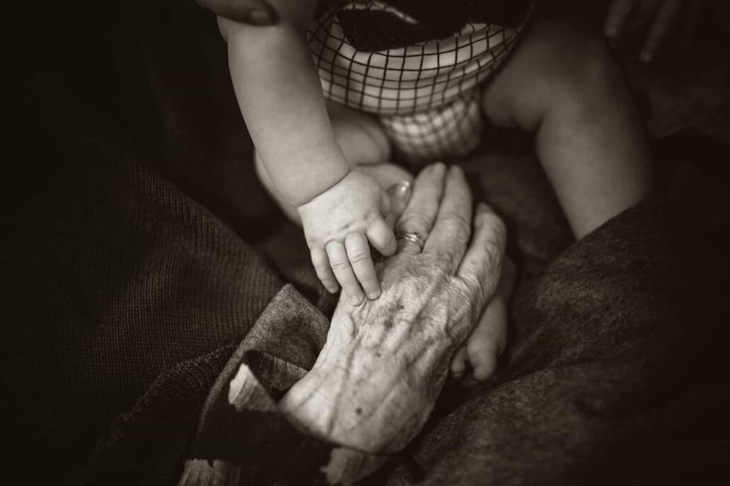Een zwart -witte close -up van de hand van een oude man met een kinderhand