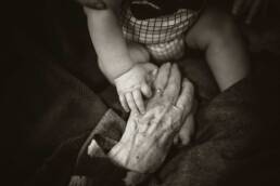 baby holding a hand of an grandparent
